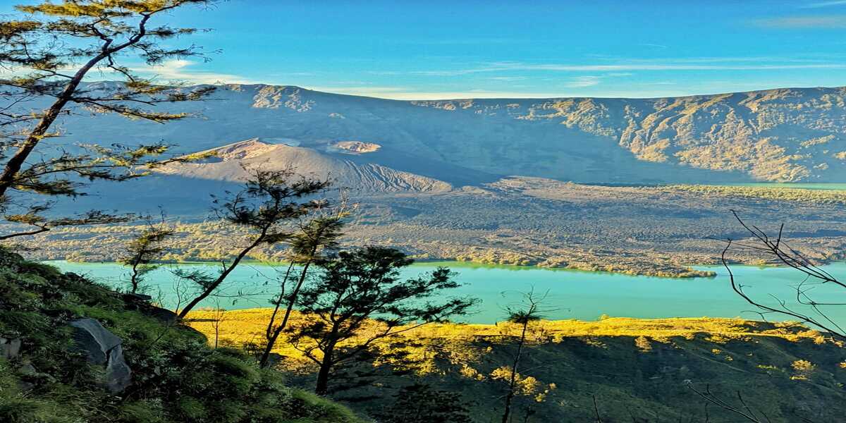 Hikers standing on the ridge of Mount Rinjani at sunrise, overlooking the stunning Segara Anak crater lake and the volcanic landscape of Lombok, Indonesia.