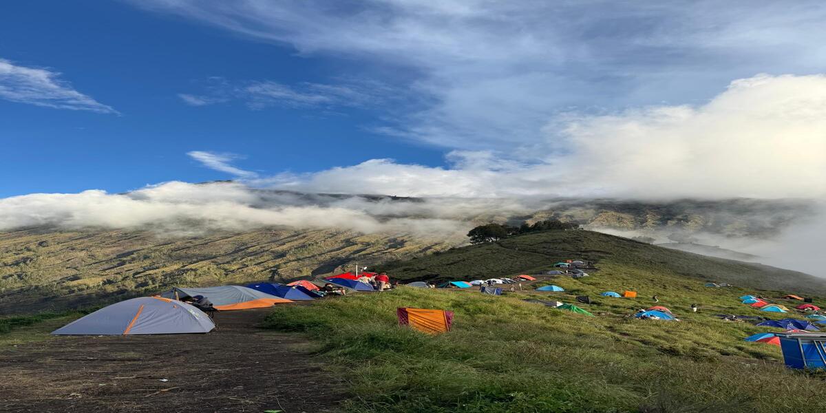 Camping tents set up on Mount Rinjani with panoramic views of the volcanic landscape.